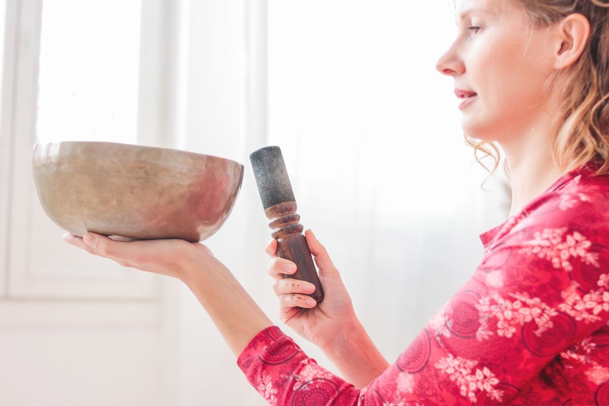 Young woman playing on brass Tibetan singing bowl. Sound therapy and meditation